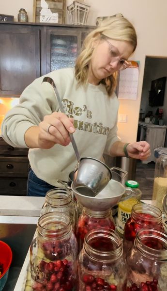 Preparing the jars of cranberry juice. Ladel boiling water into each jar.