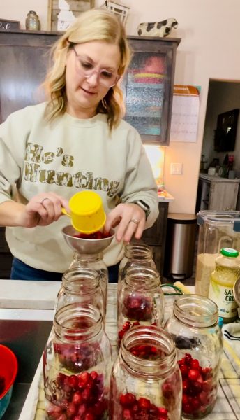 Preparing the jars of cranberry juice. Filling each jar with fresh cranberries.