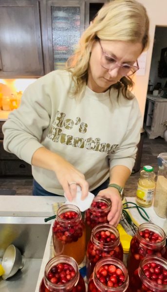 Preparing the jars of cranberry juice. wiping the rims of each jar after filling.